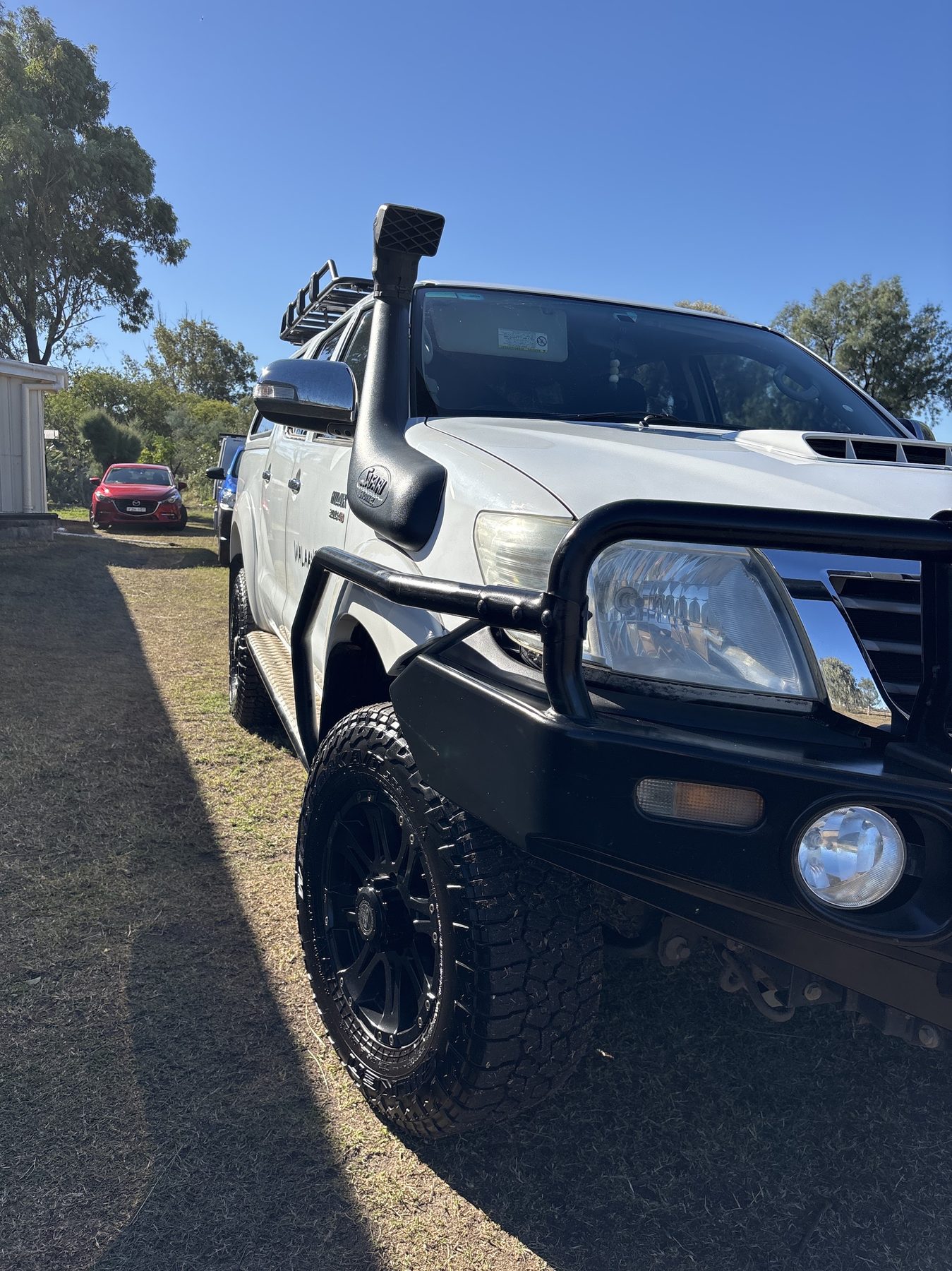 A finished white Toyota HiLux with a snorkel and bullbar after detailing